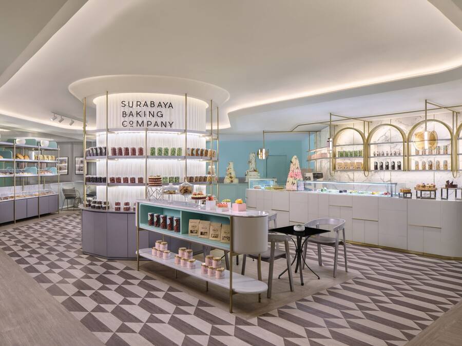 A modern bakery with a central display, shelves with baked goods, and a patterned floor.