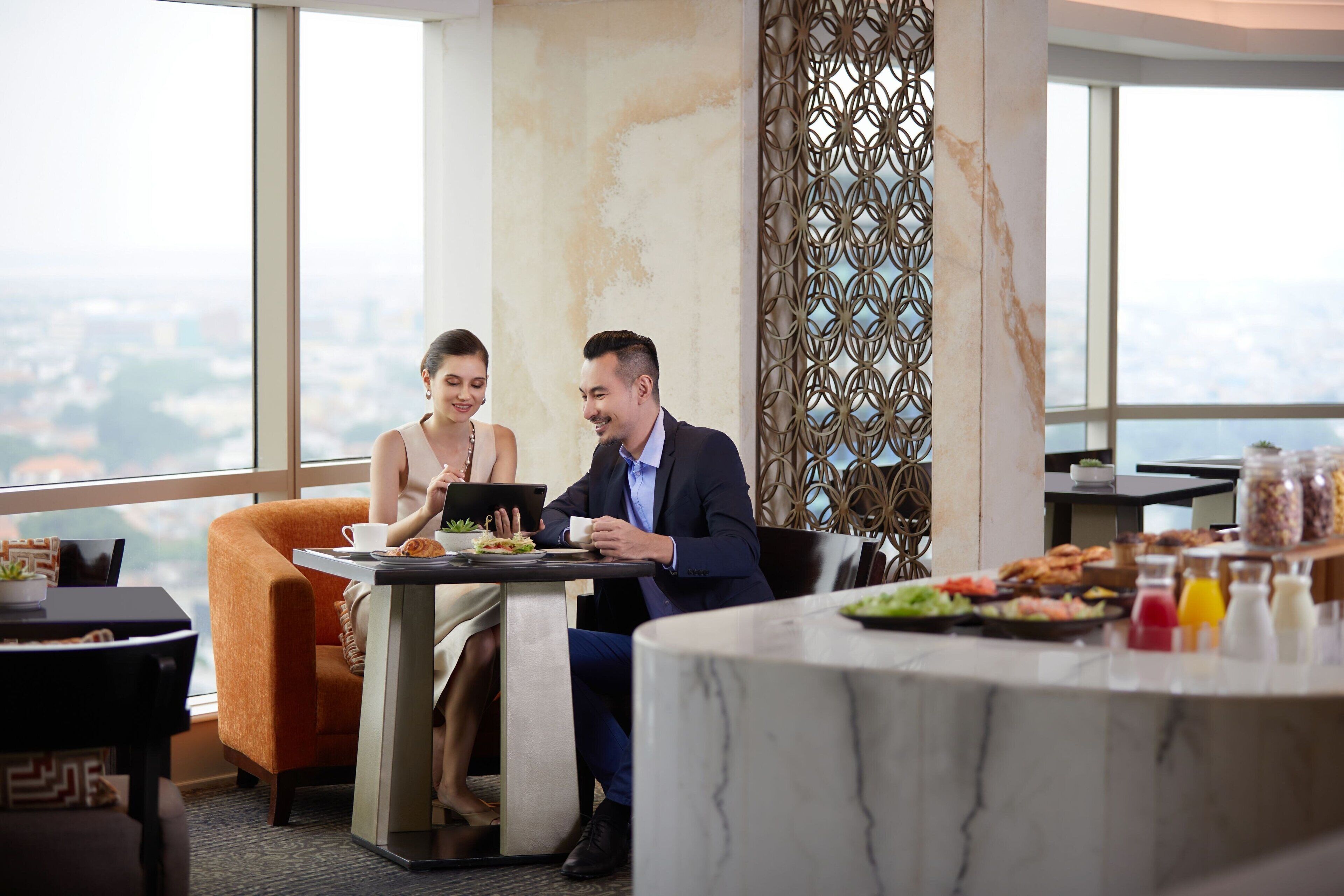A modern dining area with a city view, a decorative wall, and a buffet table with various food items.