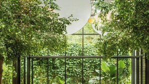 An indoor space with a glass ceiling, green plants, and a seating area with a table and chairs. - JW Marriott Surabaya (Surabaya)