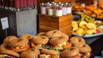 Un buffet proposant des sandwichs aux bagels, une variété de fruits et un coin boissons.
