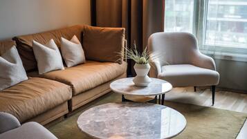 A modern living room with a sofa, armchair, round coffee table, and a potted plant.