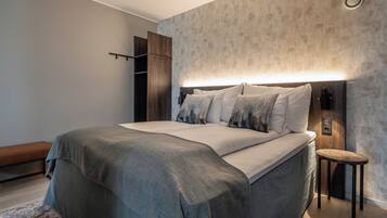 Un dormitorio moderno con una cama grande, una mesita de noche y un armario.