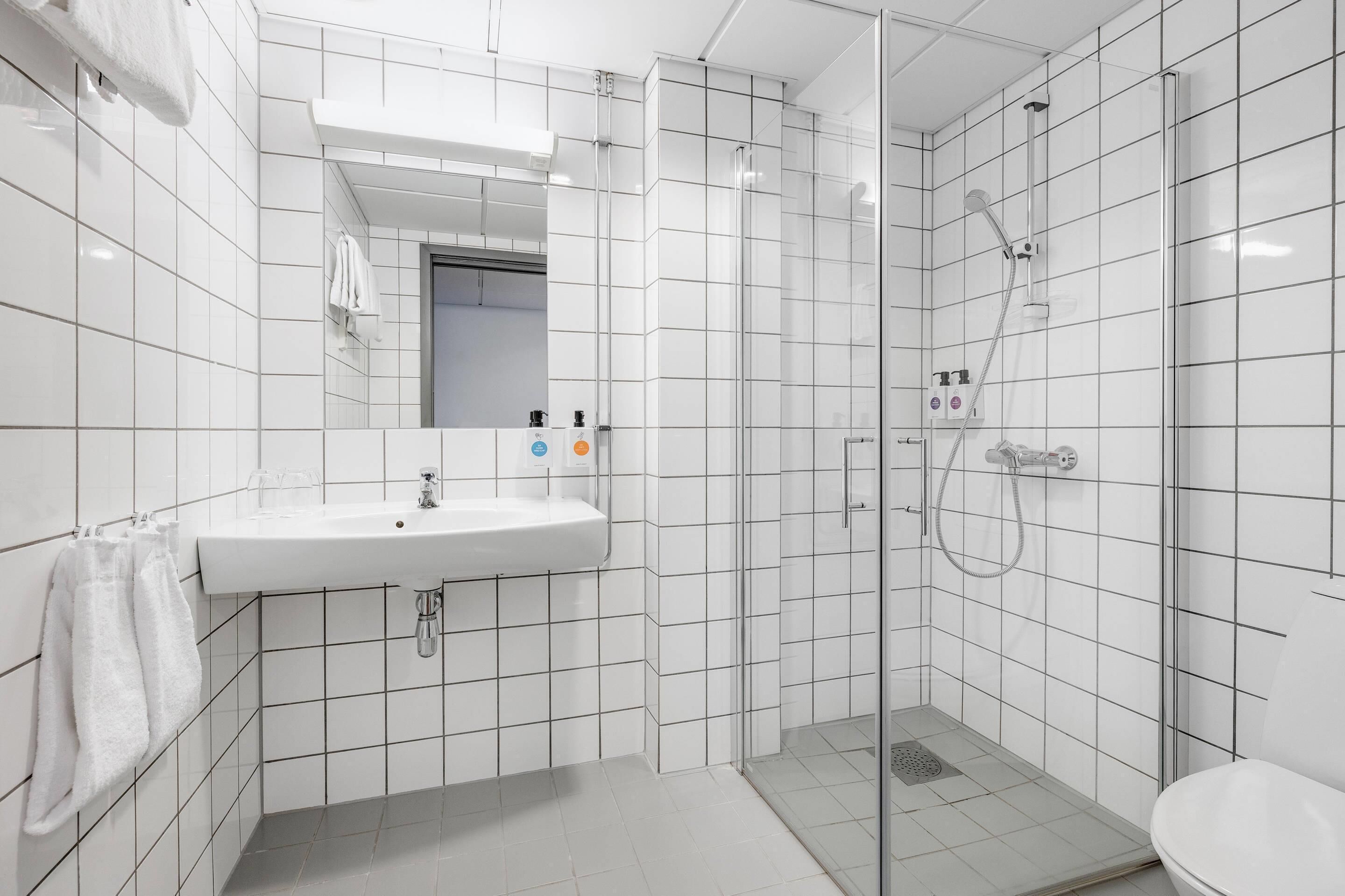 A modern bathroom with a white sink, mirror, and shower.