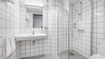 A modern bathroom with a white sink, mirror, and shower.