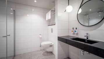 Ein modernes Badezimmer mit Toilette in Weiß, einem schwarzen Waschtisch und einer Duschkabine.