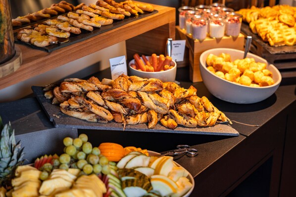 Un bufé con distintos alimentos, entre ellos pasteles, carnes y frutas.