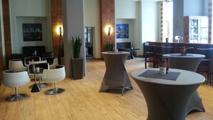 A modern lobby with round tables, comfortable seating, and large windows allowing natural light. - Wyndham Duisburger Hof (Duisburg)