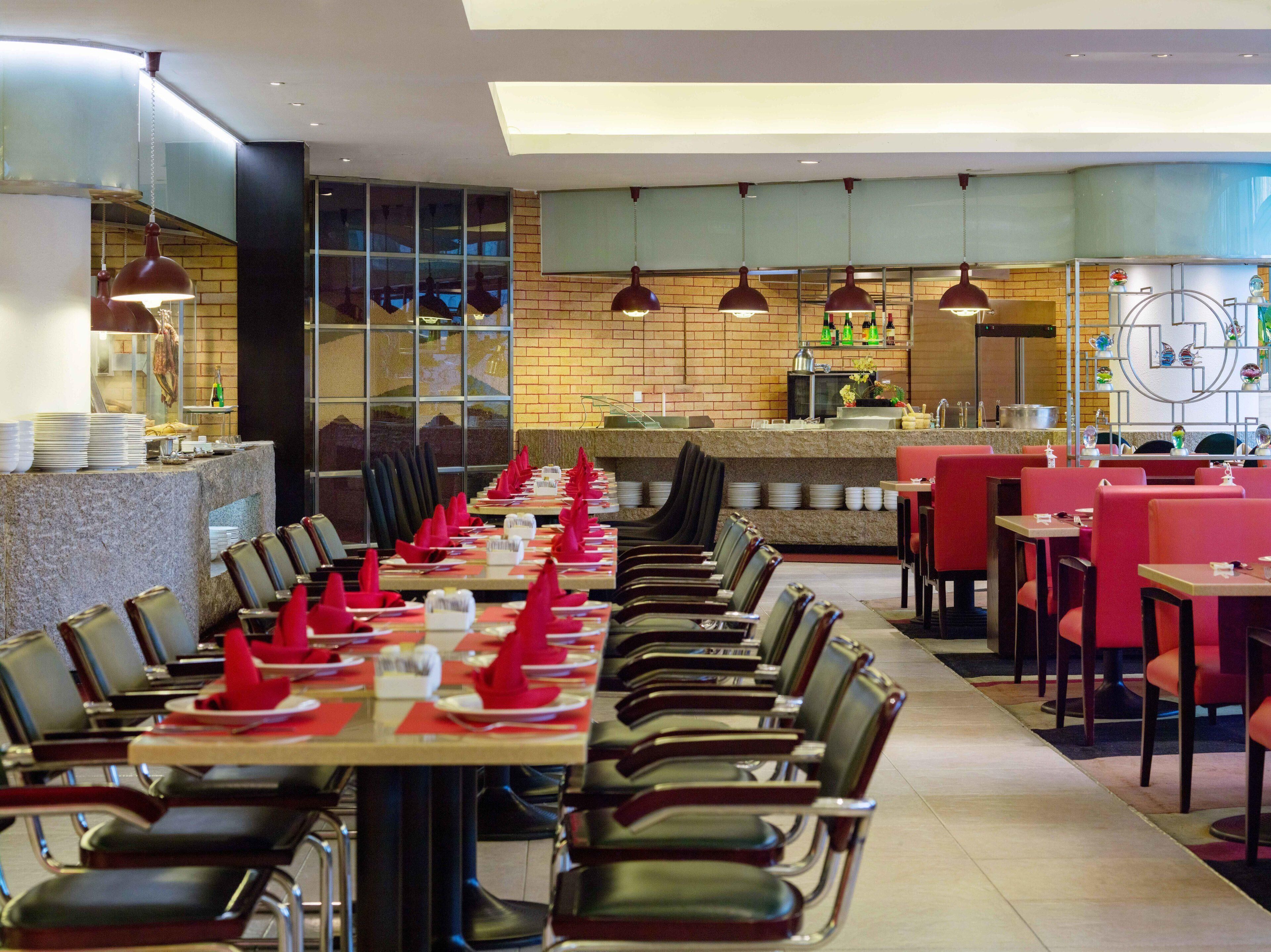 Un restaurante con mesas largas, servilletas rojas y una pared de ladrillo.