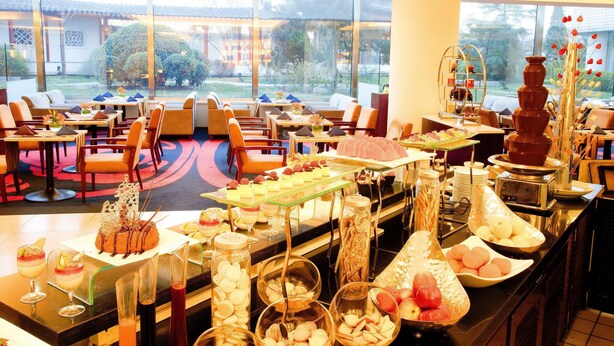 A hotel dining area with a buffet, seating, and a view of the outdoors. - Beijing Landmark Hotel (Beijing)