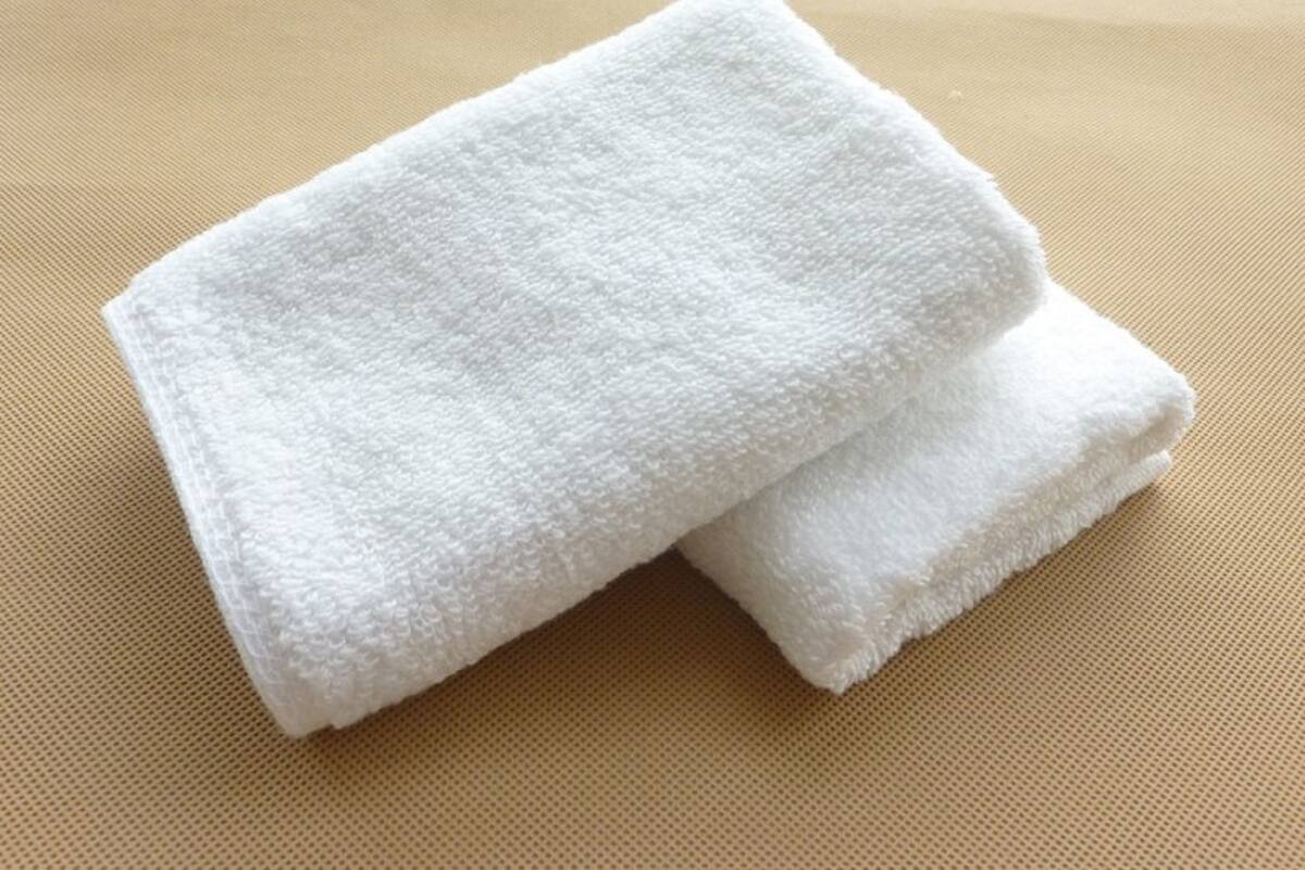 Una toalla blanca doblada sobre una superficie beige con textura.