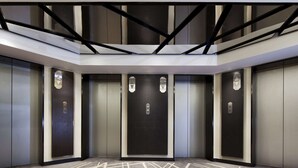 A modern elevator area with five elevators, a geometric ceiling design, and a patterned carpet. - Beijing Landmark Hotel (Beijing)