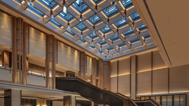 Un hall amplio con una escalera central, una zona de recepción y un tragaluz grande.