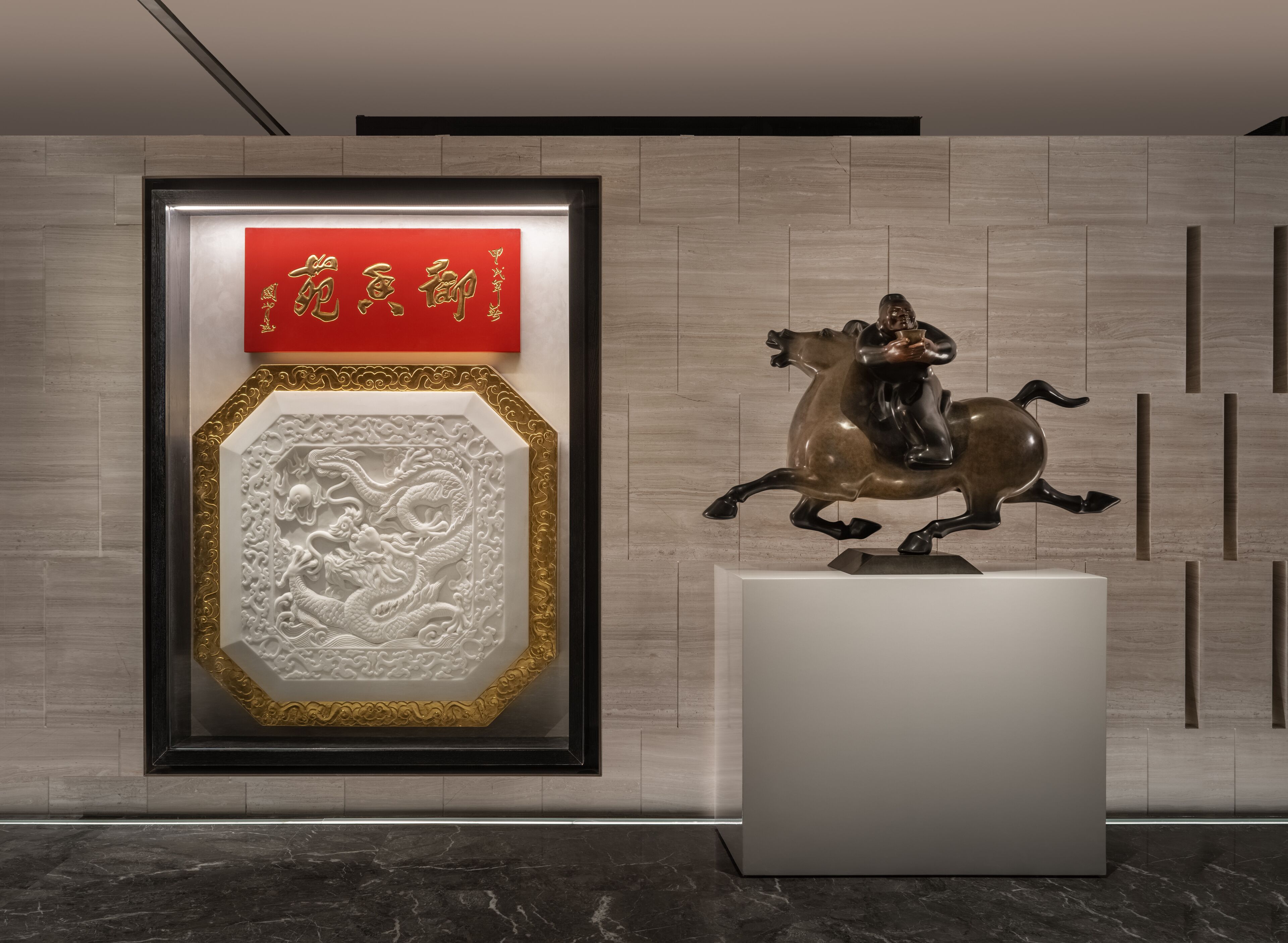 A framed artwork with a dragon design and Chinese characters, a statue of a person on a horse, and a red sign with Chinese characters.
