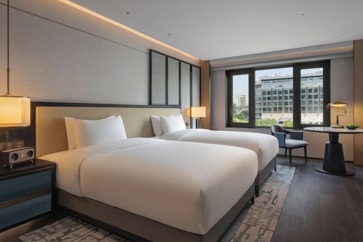 A hotel room with two beds, a desk, and a chair.