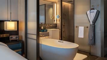 A modern bathroom with a freestanding bathtub, a vanity with a mirror, and a robe hanging on a hook.