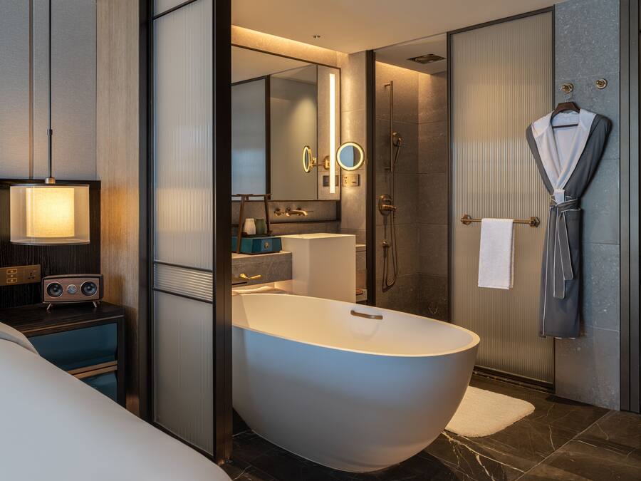 A modern bathroom with a freestanding bathtub, a vanity with a mirror, and a robe hanging on a hook.