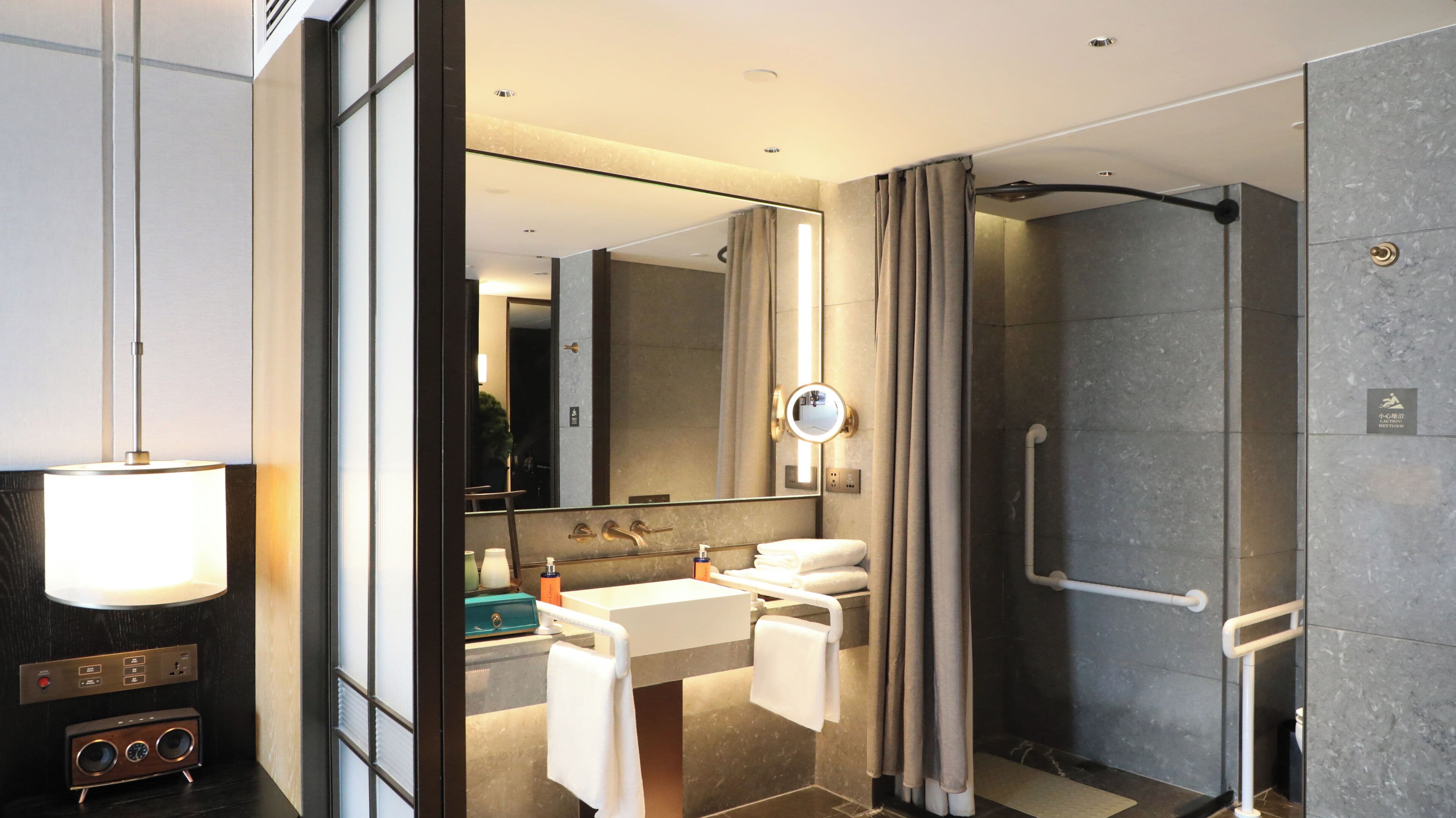 A modern bathroom with a large mirror, a sink, a shower, and a walk-in shower stall.