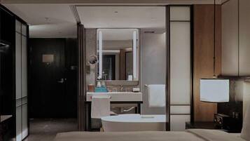 Una camera d'albergo moderna con un letto grande, un bagno con uno specchio e un comodino.