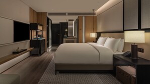 Una habitación de hotel moderna con una cama grande, mesitas de noche, un televisor y un escritorio.