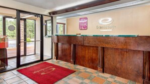A reception area with a wooden reception desk, a red carpet, and a glass door leading outside.