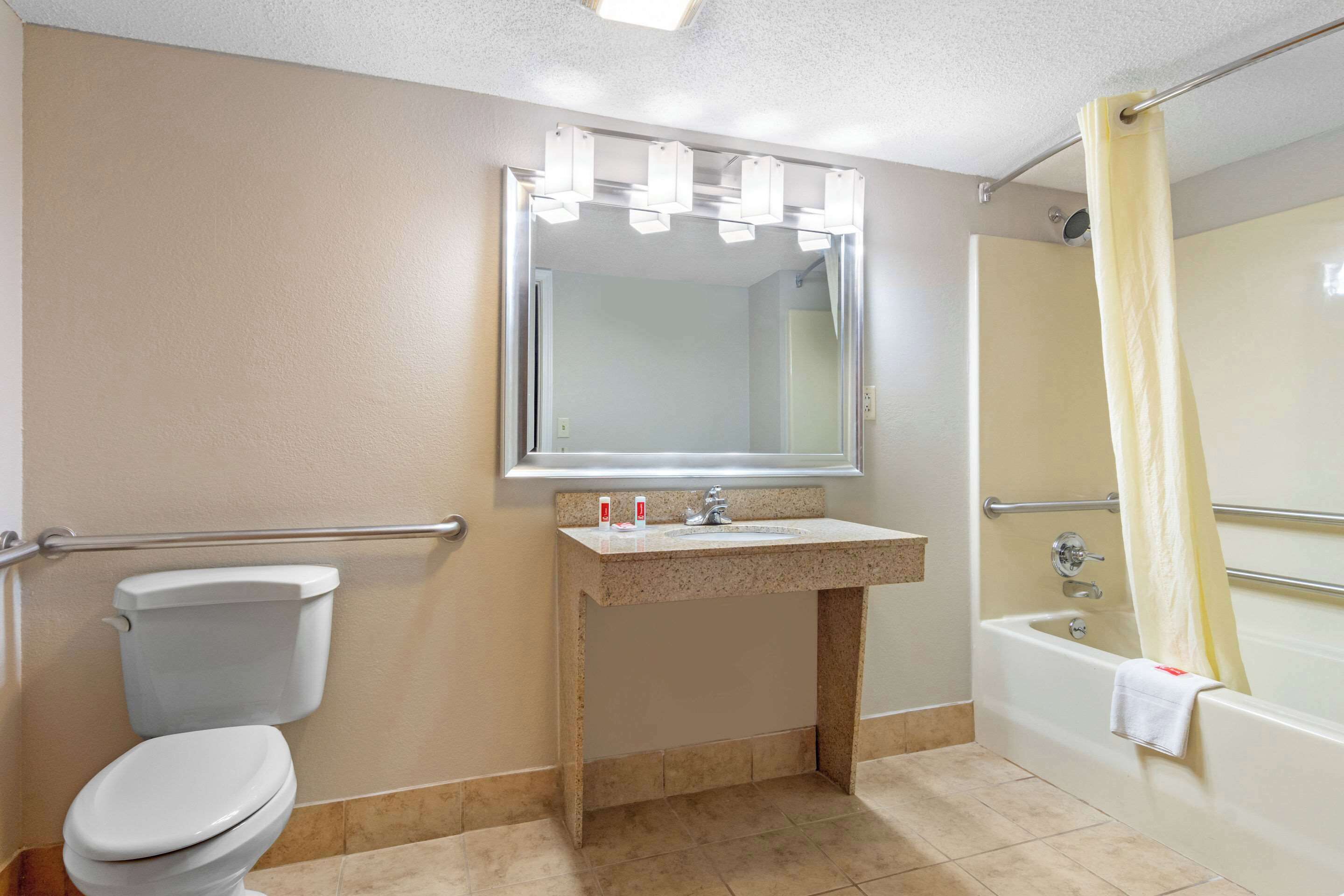 Un baño con inodoro, lavamanos, espejo y bañera.