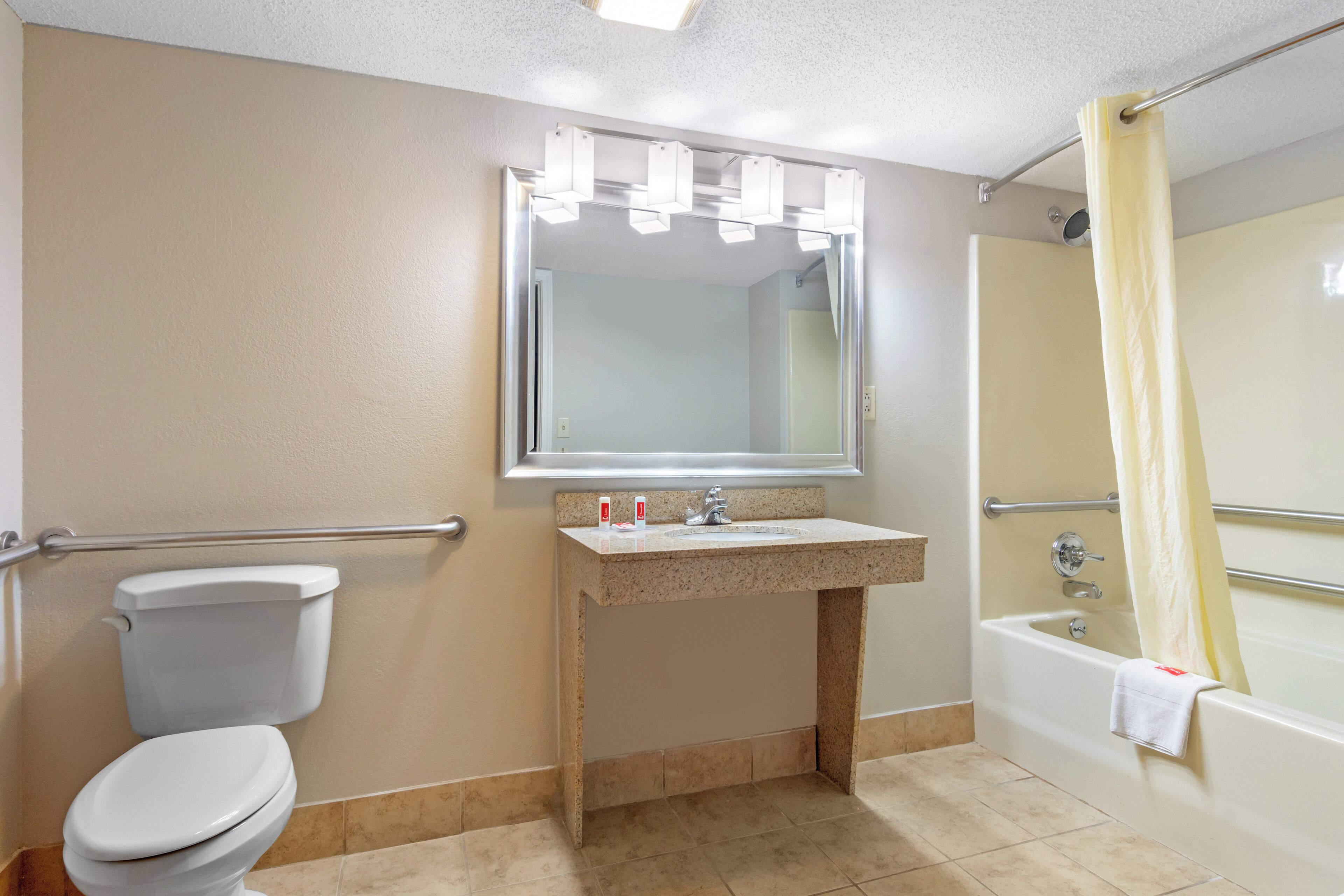 A bathroom with a toilet, sink, mirror, and bathtub.