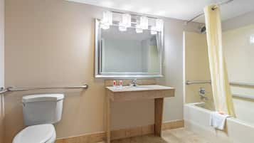 A bathroom with a toilet, sink, mirror, and bathtub.