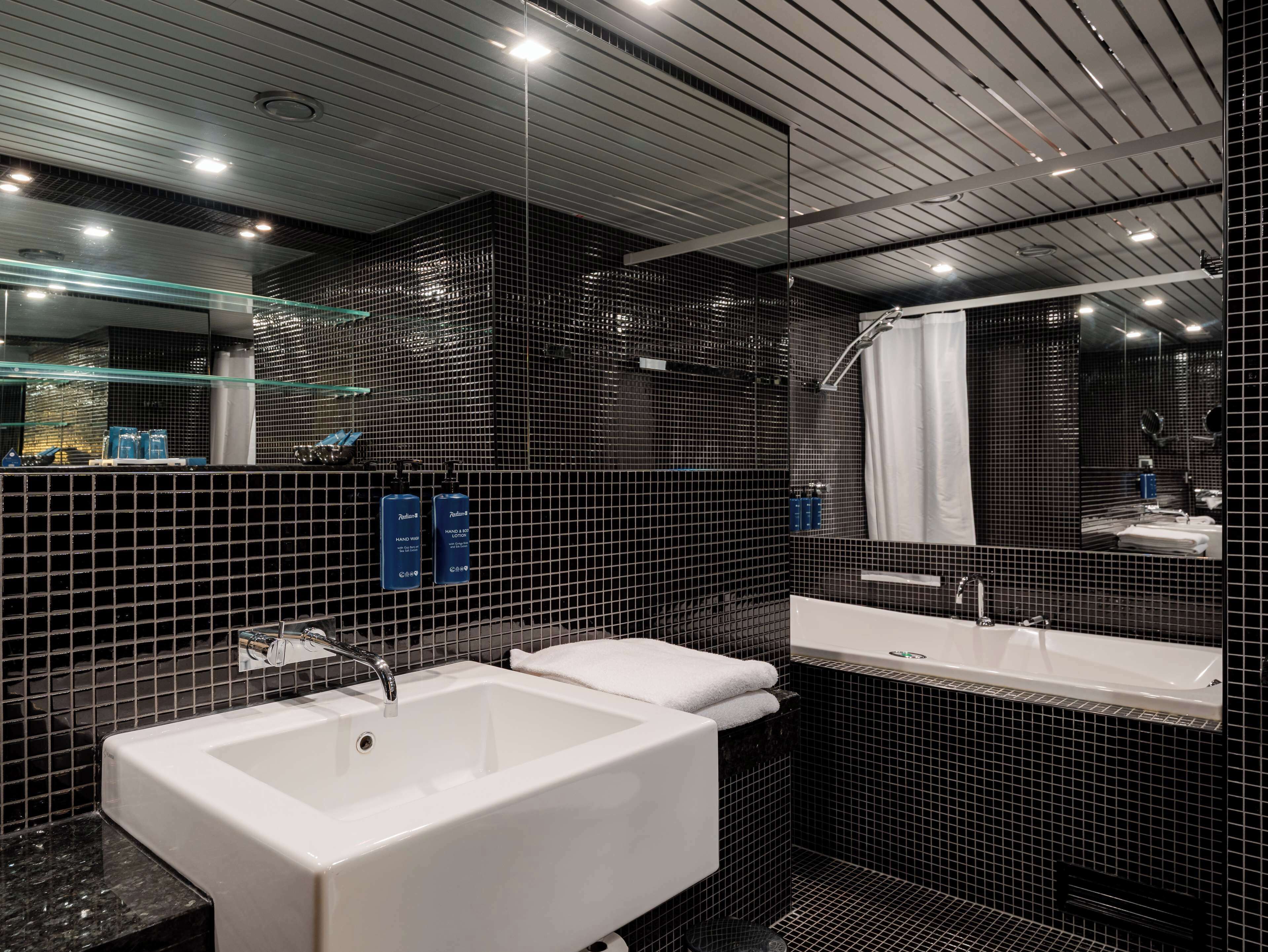 Een moderne badkamer met een groot, wit bad, een apart wastafelmeubel en een douchehoek.