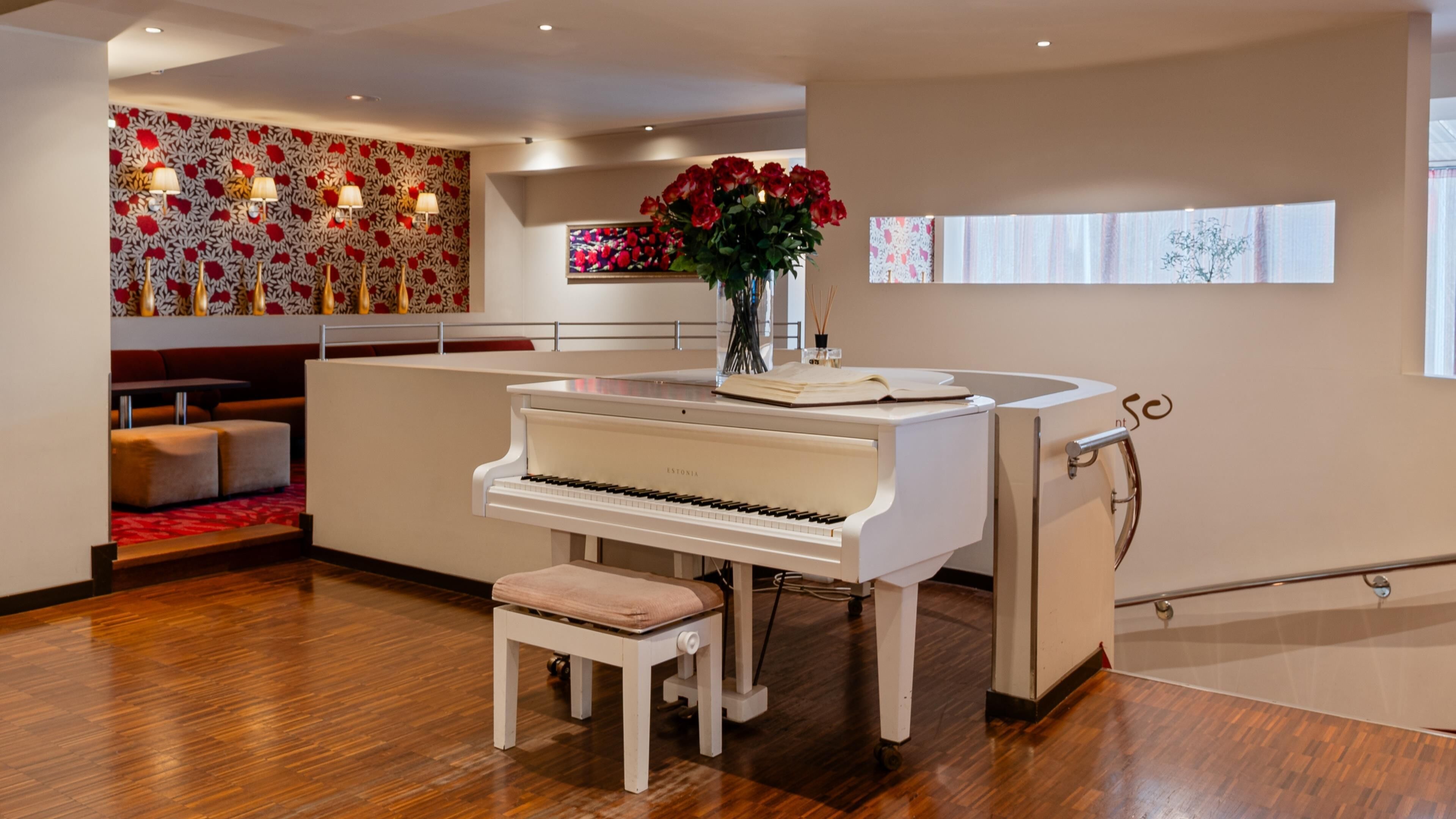 Ein modernes Interieur mit einem Flügel, einer Sitzecke und einer Wand mit floralen Mustern.