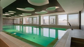 An indoor swimming pool with a city view, large windows, and a modern ceiling design. - Radisson Blu Hotel Olumpia (Tallinn)