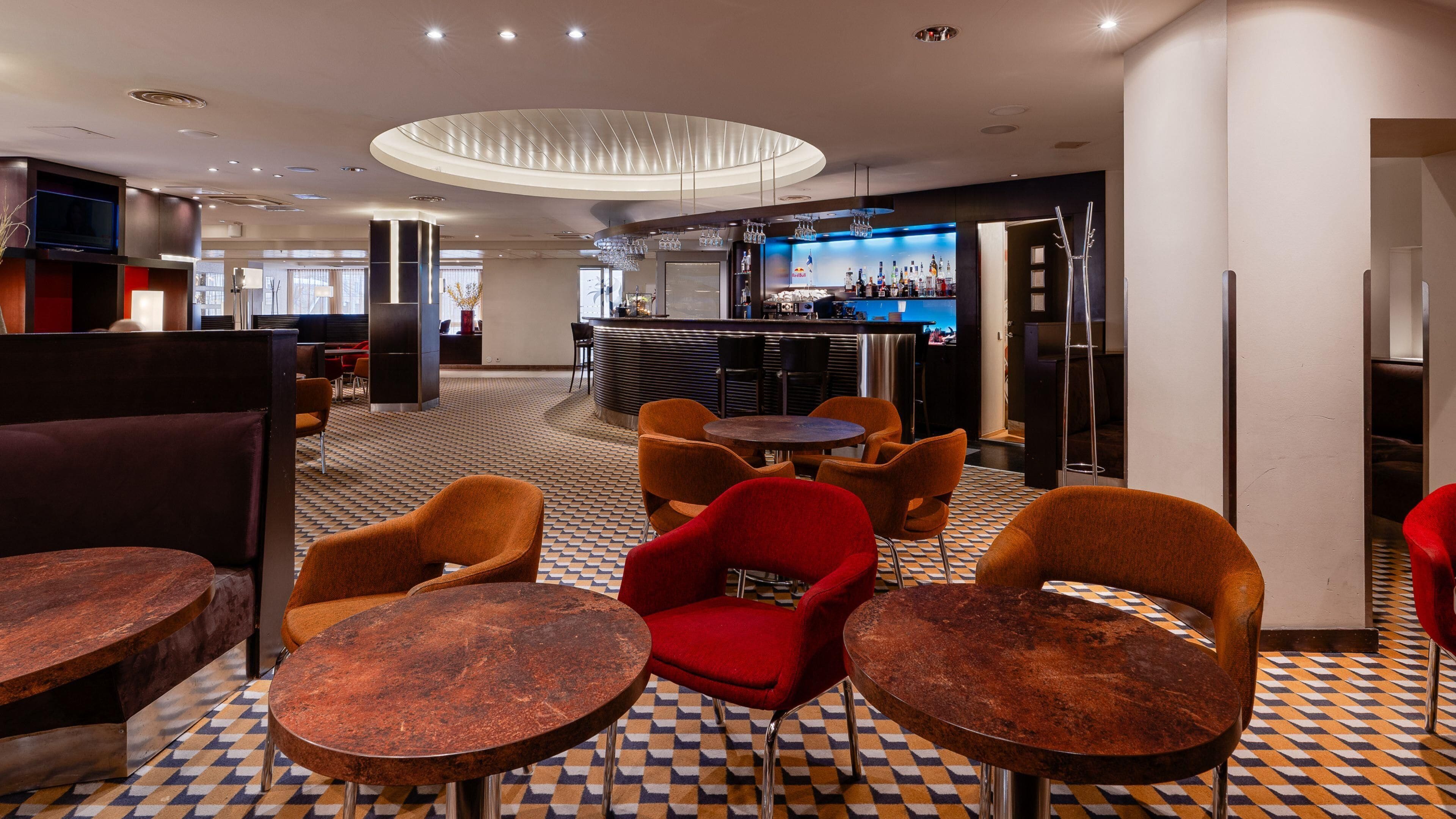 Et hotel lobby med barområde, siddepladser og et gulv med et mønster.