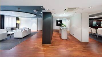 Eine moderne Hotelhalle mit einer Rezeption, einer Lounge und einer Bar.