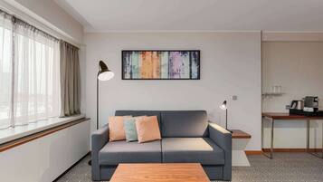 A modern living room with a grey sofa, a wooden coffee table, and a colorful abstract painting on the wall.