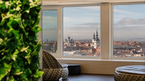 A room with large windows overlooking a cityscape with historic buildings and a prominent church tower. - Radisson Blu Hotel Olumpia (Tallinn)