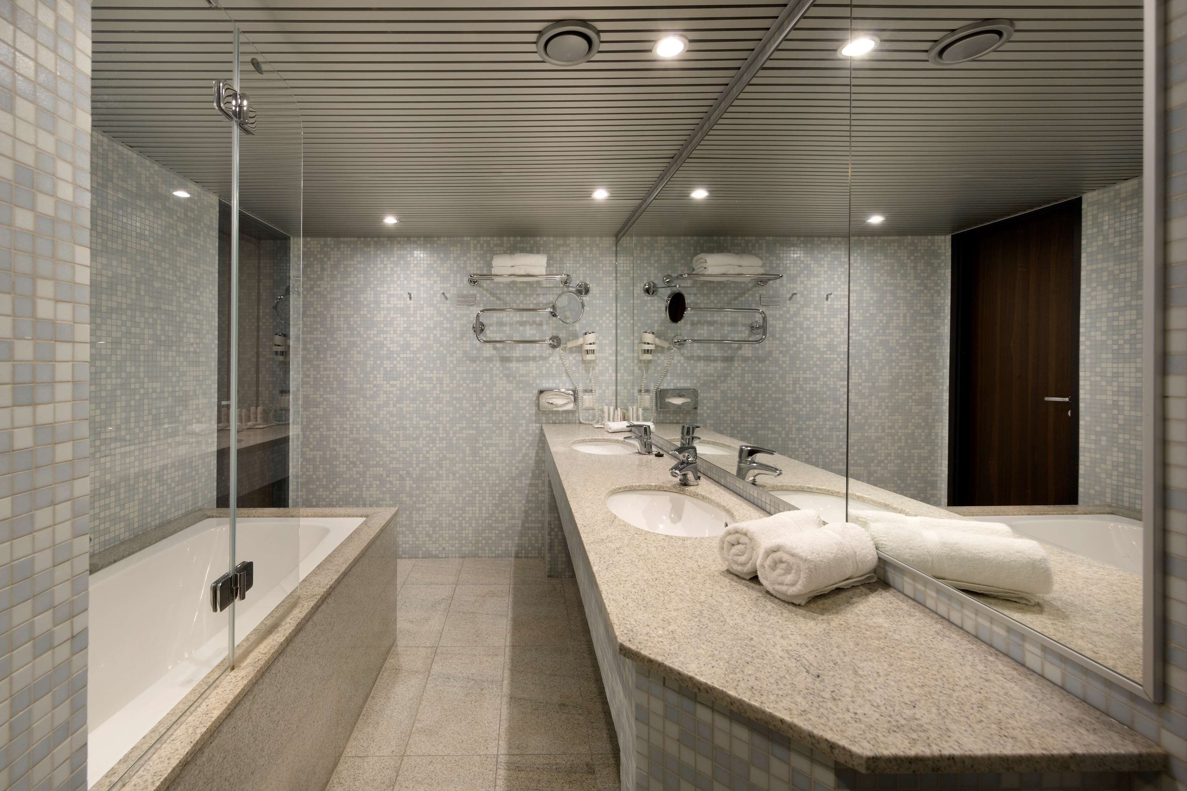 A modern bathroom with three sinks, a large mirror, and a glass-enclosed shower.