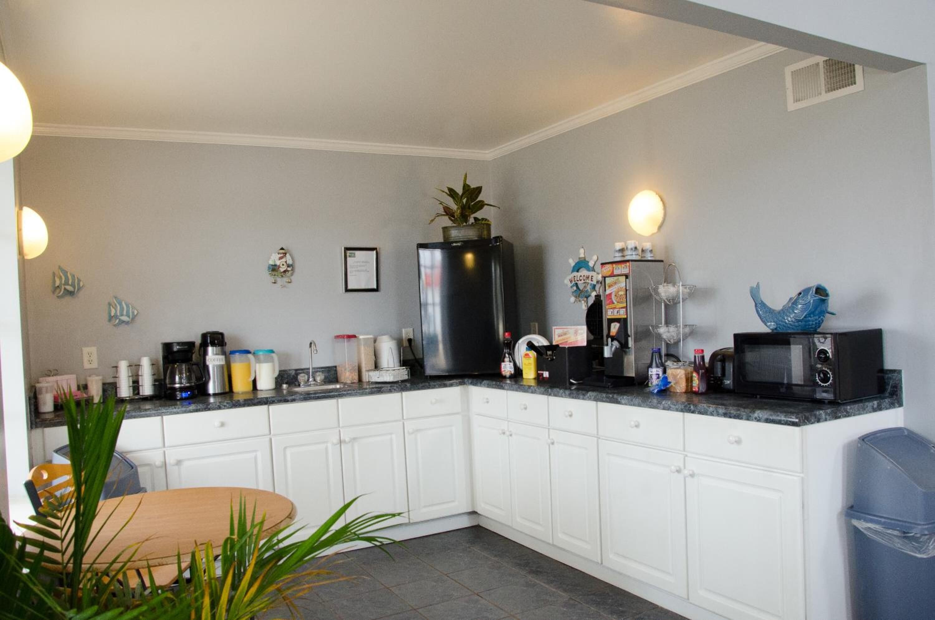 A modern kitchen with white cabinets, a black refrigerator, a microwave, and various kitchen appliances.