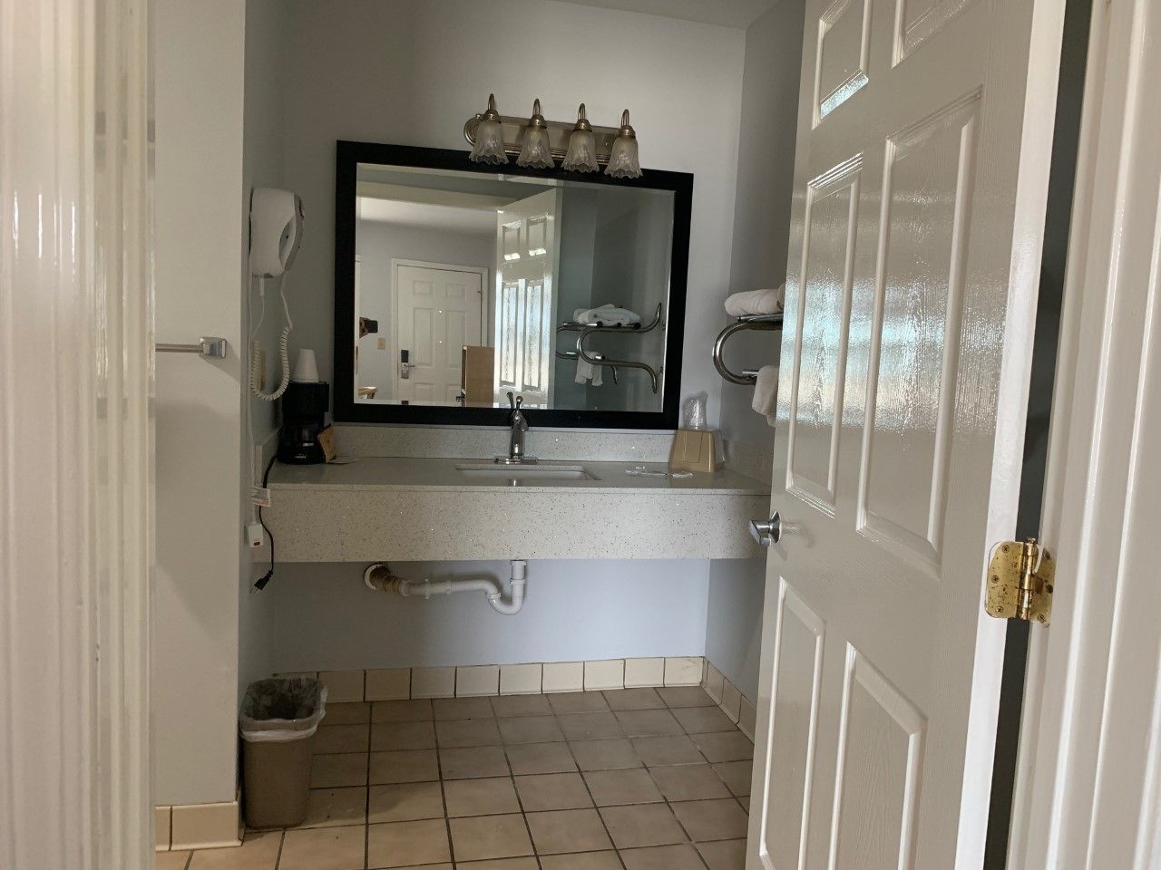 Une salle de bain avec un lavabo blanc, un miroir, un sèche-cheveux et un porte-serviettes.