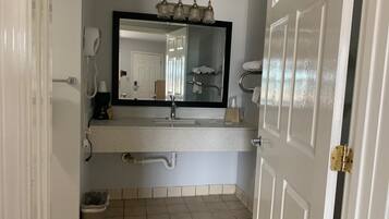 A bathroom with a white sink, a mirror, a hairdryer, and a towel rack.