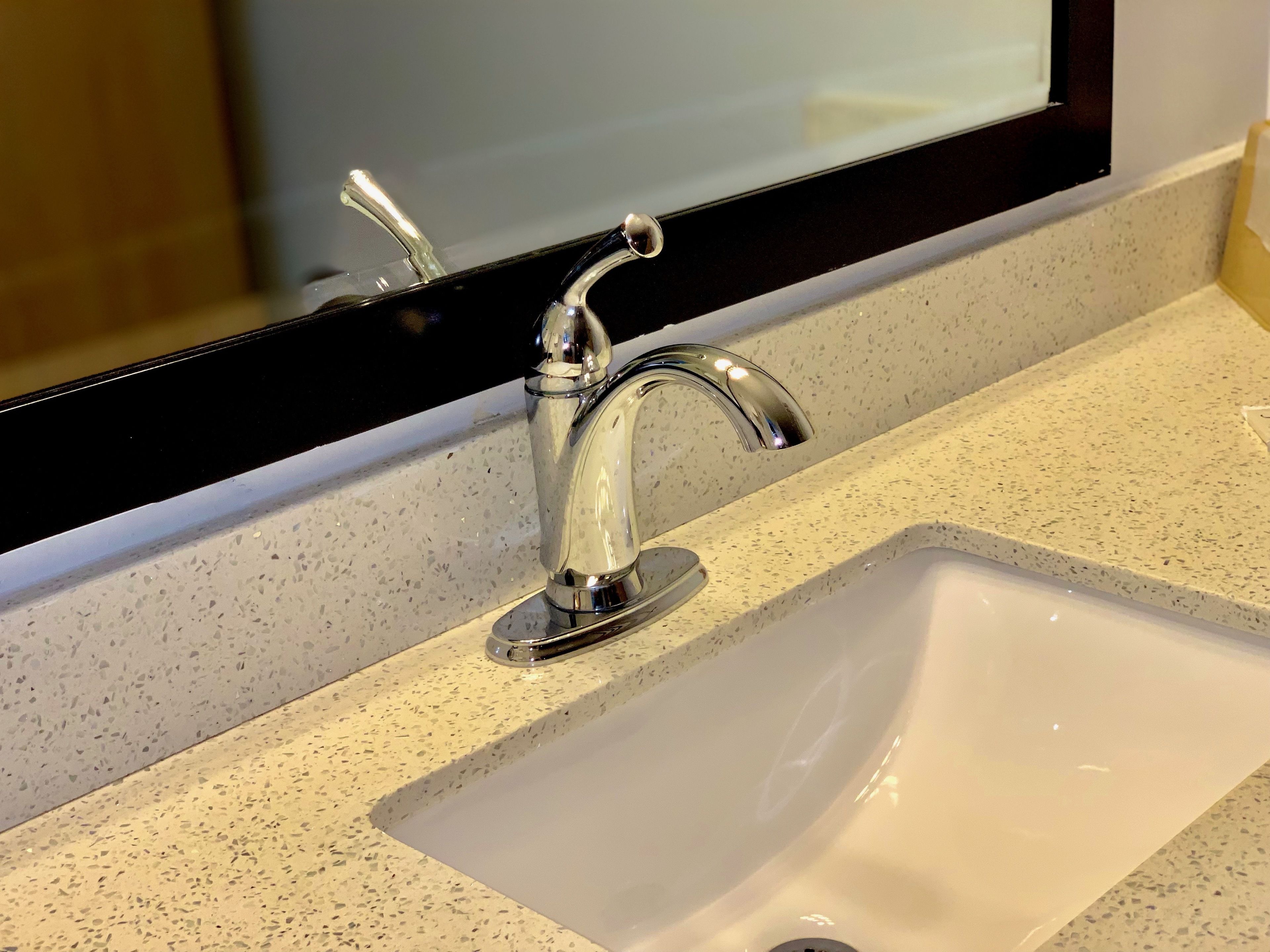 A bathroom sink with a chrome faucet and a mirror above it.