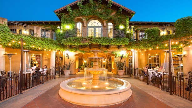 Un patio con una fuente, asientos al aire libre y un edificio con balcón.