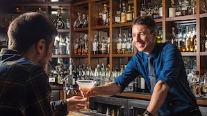 Un bar con estantes llenos de botellas de licor y vasos.