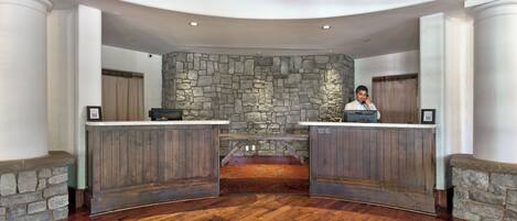 A reception area with a stone wall, wooden reception desk, and a wooden floor.
