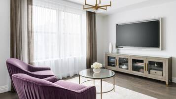 Una sala de estar moderna con un sofá púrpura, una mesa de centro de vidrio y un televisor de pantalla plana montado en la pared.