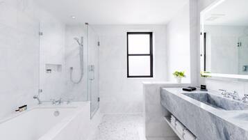 A modern bathroom with a glass-enclosed shower, a large bathtub, and a dual sink vanity.