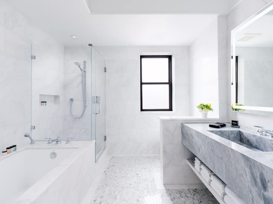 A modern bathroom with a glass-enclosed shower, a large bathtub, and a dual sink vanity.