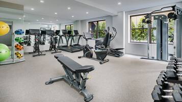 A gym with treadmills, elliptical machines, a bench press, and various exercise balls.