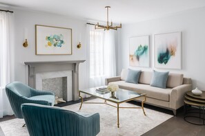 Relax in this stylish living room with a sofa, coffee table, and armchairs, surrounded by artwork and a fireplace.