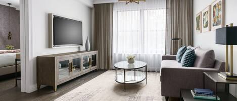 Una sala de estar moderna con sofá, mesa de centro, televisor y obra de arte en la pared.