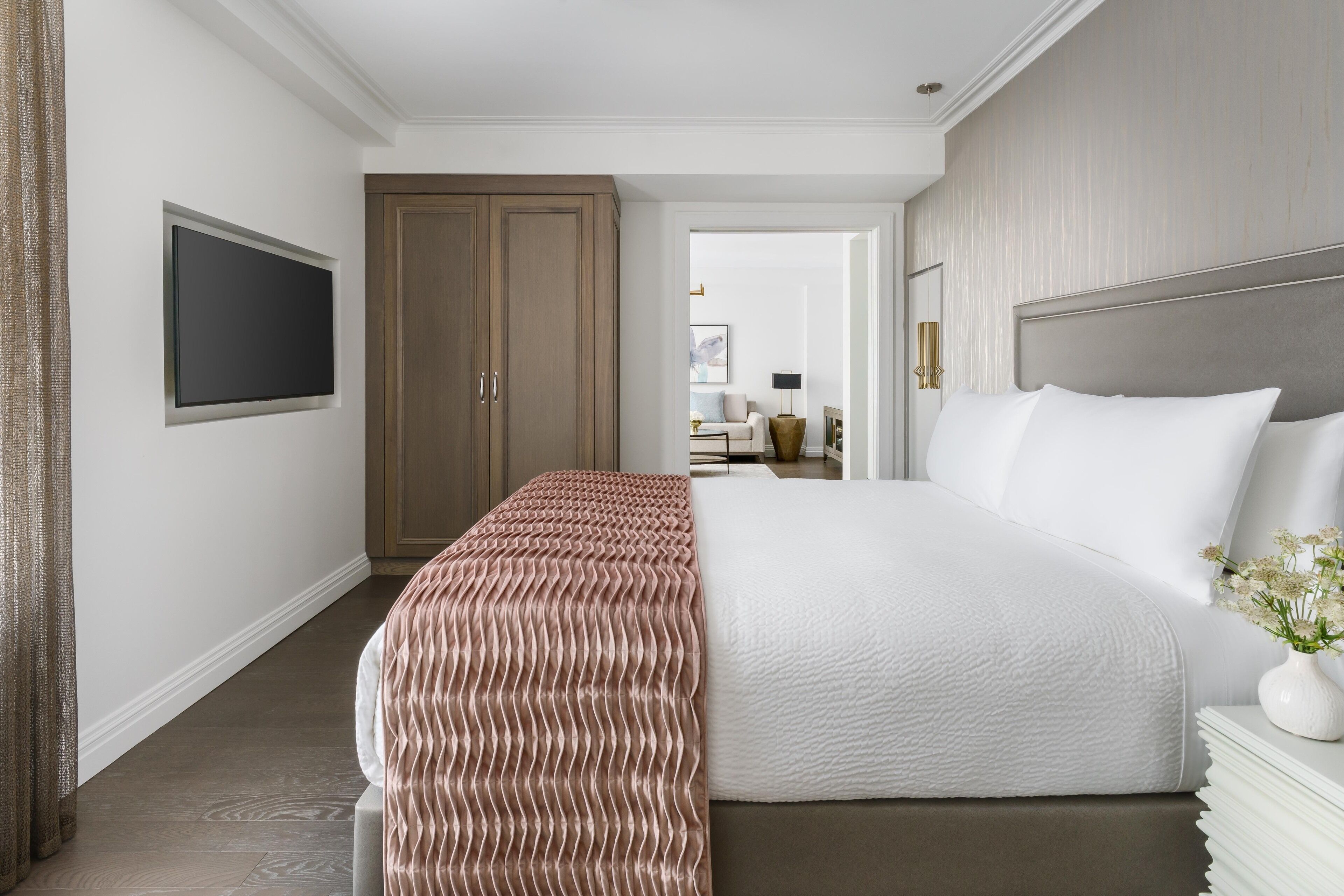 A hotel room with a large bed, a TV mounted on the wall, and a wardrobe.