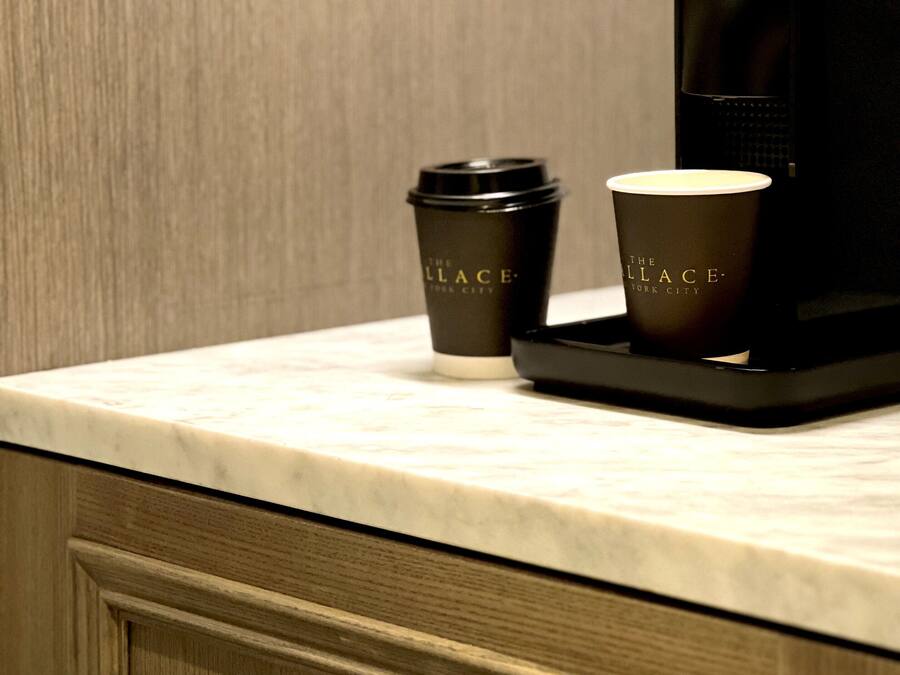 A coffee machine and two coffee cups on a marble countertop.